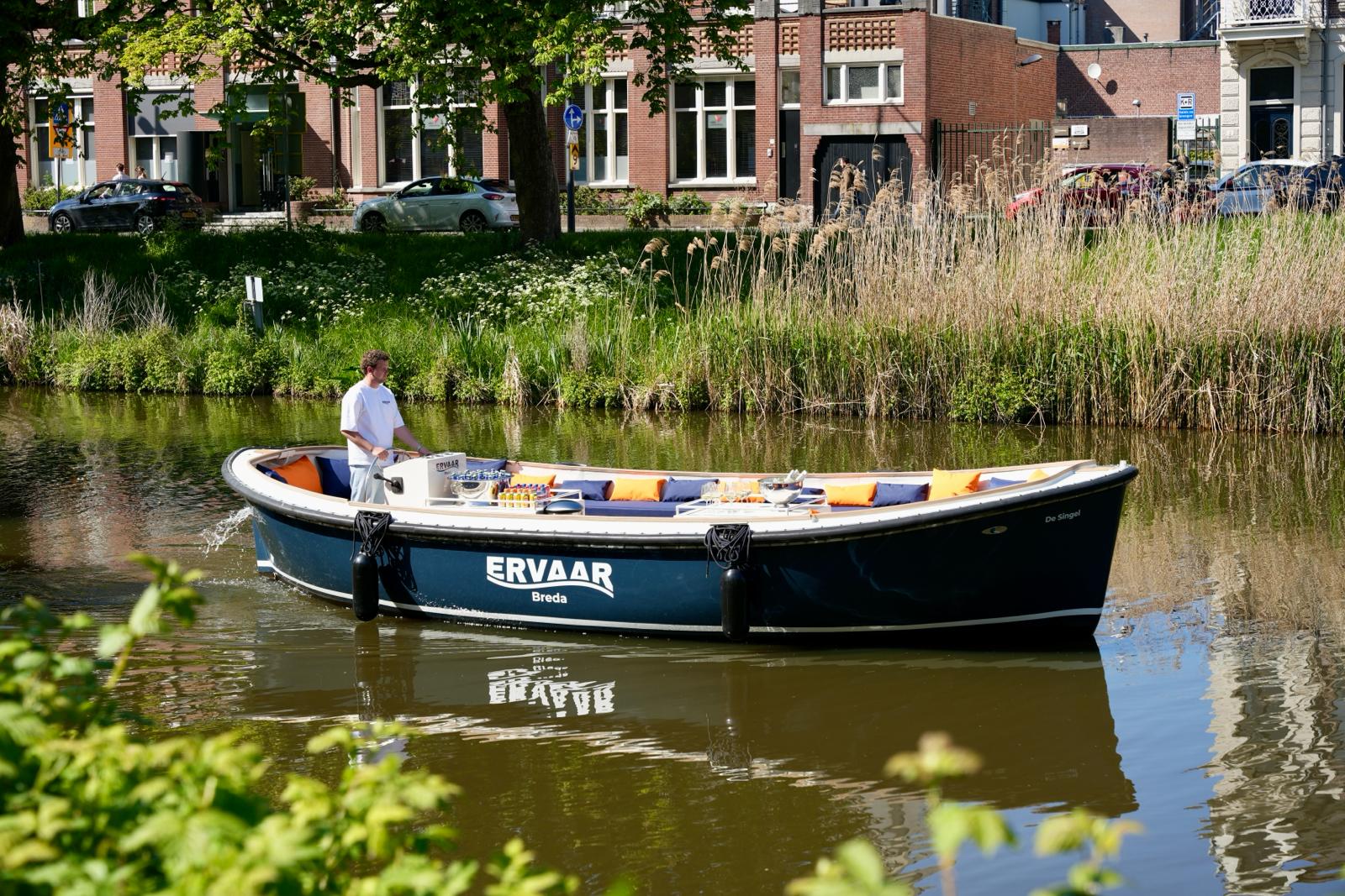 Luxe privé sloep tijdens een rondvaart door de singels van Breda met mensen aan boord, ideaal voor bootje varen Breda, sloep huren Breda, rondvaart Breda, groepsuitje, bedrijfsuitje, verjaardag en vrijgezellenfeest Breda op het water.